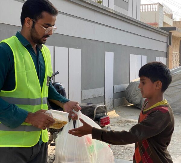 Volunteers providing cooked meals and food assistance to underprivileged people in Pakistan